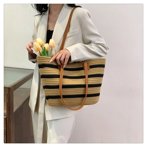 Detail view of woven cotton rope beach bag with black stripes and brown leather handles