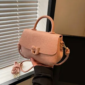 Sac selle en cuir grainé rose avec boucle en J dorée et poignée supérieure élégante
