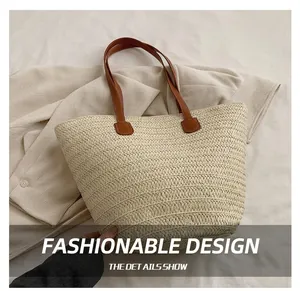 Detail of straw tote bag showing beige woven texture and brown leather strap on fabric