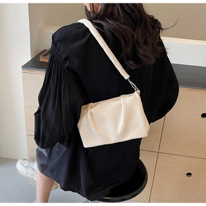 Détail du sac à bandoulière crème plissé montrant la texture douce du similicuir