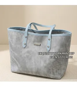 Close-up of gray twill tote bag showing light blue trim and silver metal brand plaque
