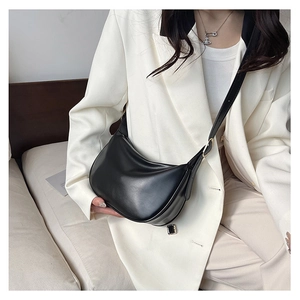 Minimalist black PU leather moon bag worn cross-body over a crisp white blazer