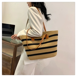 Close-up of woven tote bag with stripe patterns and leather strap in office setting