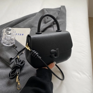 Sac selle minimaliste en cuir grainé noir avec boucle en G et détails métalliques dorés