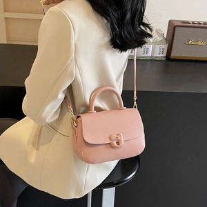 Sac selle en cuir grainé rose avec boucle métallique présenté sous un angle de 45 degrés