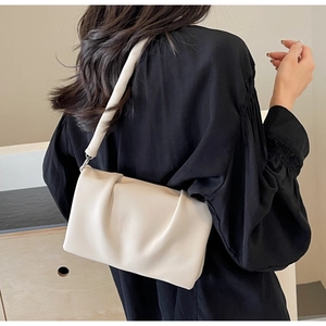 Detail of a creamy white pleated shoulder bag with soft leather texture and thick strap