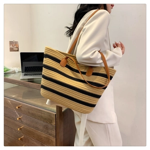 Detail of striped woven tote bag featuring premium leather shoulder straps and large capacity