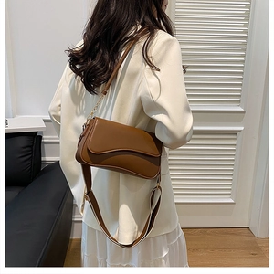 Sac à bandoulière en cuir marron avec rabat incurvé sur une tenue de blazer blanc