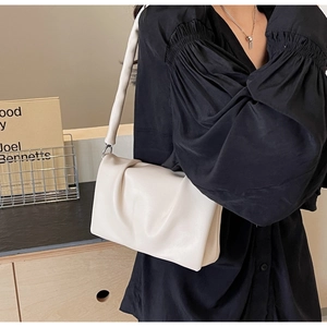 Detail of white pleated leather bag with wide shoulder strap and silver metal buckle
