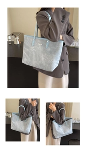 Macro shot of light blue marble texture fabric and silver logo plate on large tote bag