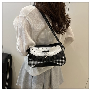 Detail of a black and white handbag with heart patterns and ruffle edges on a model