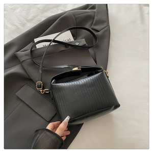 Detail of black pleated texture bag with golden metal hardware and smooth wide handle