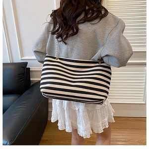 Close-up of black and white striped canvas tote bag with elegant gold chain strap