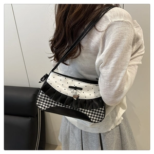 Detail showing checkered patterns, heart prints, and a bow on a stylish underarm bag