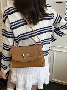 Classic brown textured tote bag with metal buckle shown on a model for scale