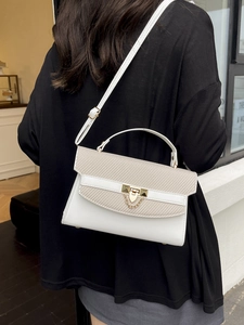 Minimalist white and beige woven crossbody bag with gold lock and chain shown on model