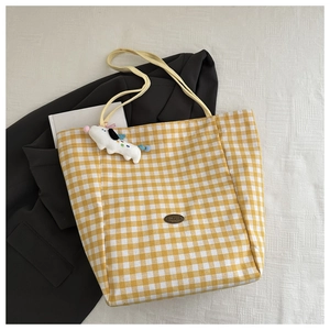 Détail du sac fourre-tout en toile à carreaux jaunes avec étiquette cuir et charme chien