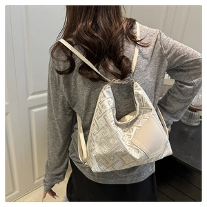 Detail of the geometric maze texture and adjustable strap on the cream shoulder bag