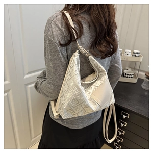 Gros plan du tissu jacquard beige à texture florale géométrique sur ce sac à bandoulière