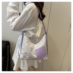Detail of purple jacquard handbag with geometric patterns and leather trim on model