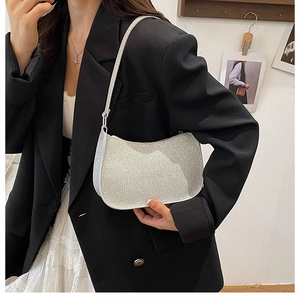 Detail of silver sequined hobo bag on a model wearing a black blazer and white skirt