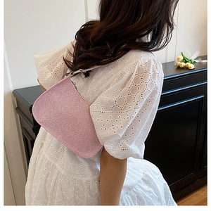Gros plan d'un sac baguette rose pailleté en forme de lune sur une robe en dentelle