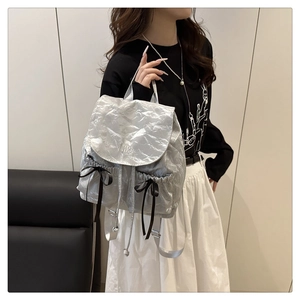 Sac à dos argenté métallisé avec nœuds et broderie Nika porté par un mannequin