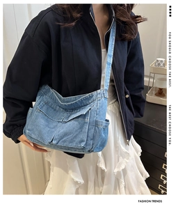 Detailed view of washed blue denim crossbody bag featuring multi-pocket utility design