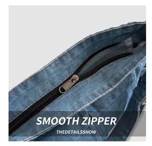 Detailed close-up of the smooth black zipper and denim fabric on a shoulder bag