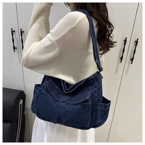 Detail of dark blue denim tote bag showing multi-pocket design and retro texture