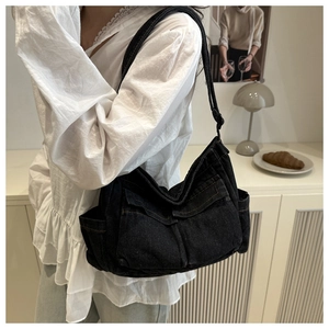 Detail of black denim crossbody bag with utility pockets and contrast yellow stitching
