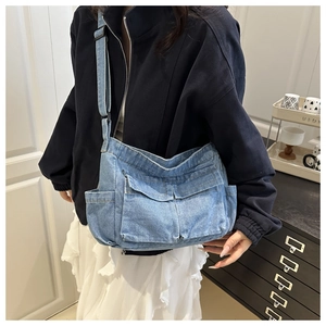 Detail view of the light blue denim crossbody bag featuring functional cargo pockets