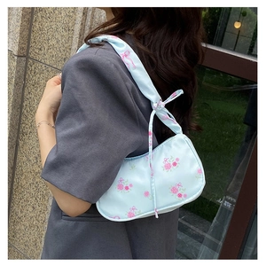 Detail view of light blue shoulder bag with floral rose print and bow accents