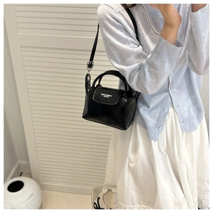 Dettaglio di una mini borsa nera a tracolla con fibbie argentate e stile moderno