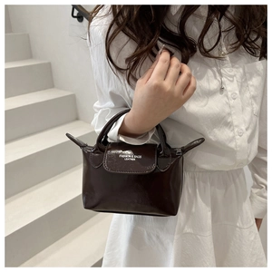 Détail d'un mini sac à main marron foncé avec finition brillante et logo sur le rabat