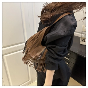 Primer plano de bolso hobo marrón con flecos largos de estilo bohemio y correa