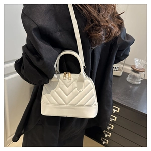 Sac à main blanc matelassé en forme de coquillage avec coutures en V et détails dorés