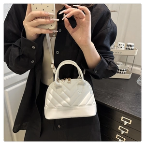 Close-up of white V-quilted shell bag with gold hardware and long shoulder strap