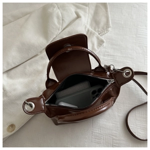 Interior view of brown glossy leather dumpling bag with smartphone and accessories
