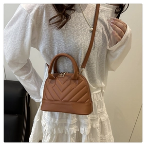 Detail of caramel shell bag with V-quilted stitching and adjustable shoulder strap