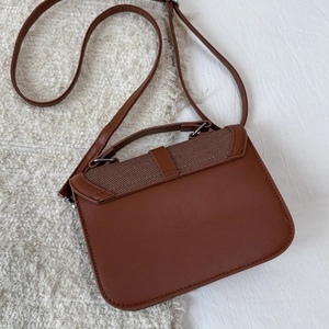 Detail of caramel brown PU leather crossbody bag with woven texture and top handle
