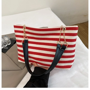 Detail of red and white striped tote bag with black handles and gold chain links