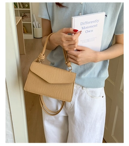 Détail du sac beige à texture tissée avec poignée nouée et anneaux métalliques