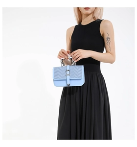 Detail of light blue handbag with woven pattern lid and sleek silver metal handle