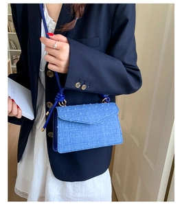 Detail of blue denim crossbody bag with textured fringe and slim rope shoulder strap
