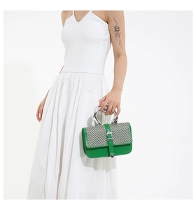 Détail du sac à main en cuir vert avec motif chevrons et poignée argentée courbée