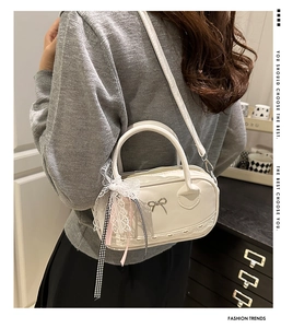 Close-up of cream white handbag featuring a silver metal bow and lace ribbon accessory