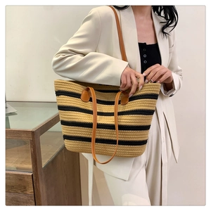 Detail showing woven straw texture and dual leather straps on striped beach tote bag