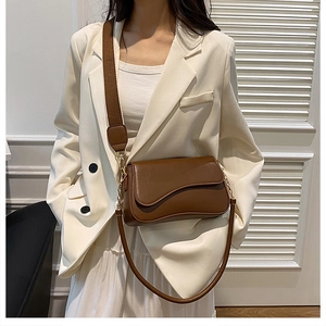 Détail du sac bandoulière en cuir marron foncé avec rabat asymétrique et double sangle