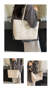 Detail of a large cream tote bag showing the fine leather texture and metal brand plate